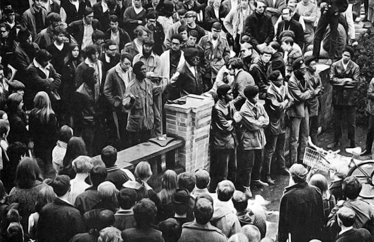 Photo of the Eugene Black Panthers speak on the UO campus in support of a Black student protest at Oregon State University in the late Sixties. From left to right: Oliver Patterson, Tommy Anderson (speaking), Howard Anderson, William Green, Jerome Foster, Julius Hurst, Dennis White, Darrell Fields, Teo DeRuso and Artie Cox.