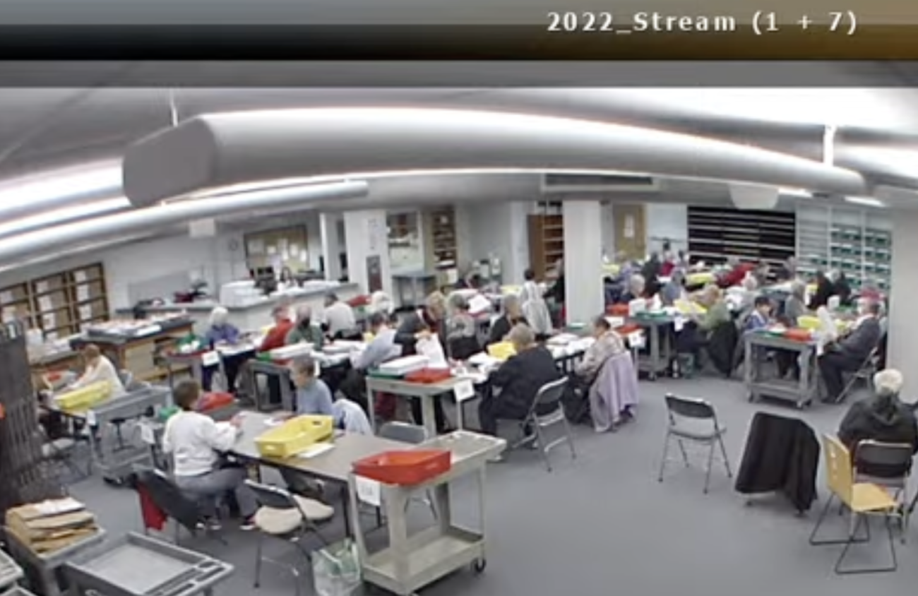 People processing ballots at desks in a large room