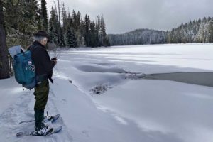 Scott Hovis on snowshoes by the frozen shore of Marilyn Lakes