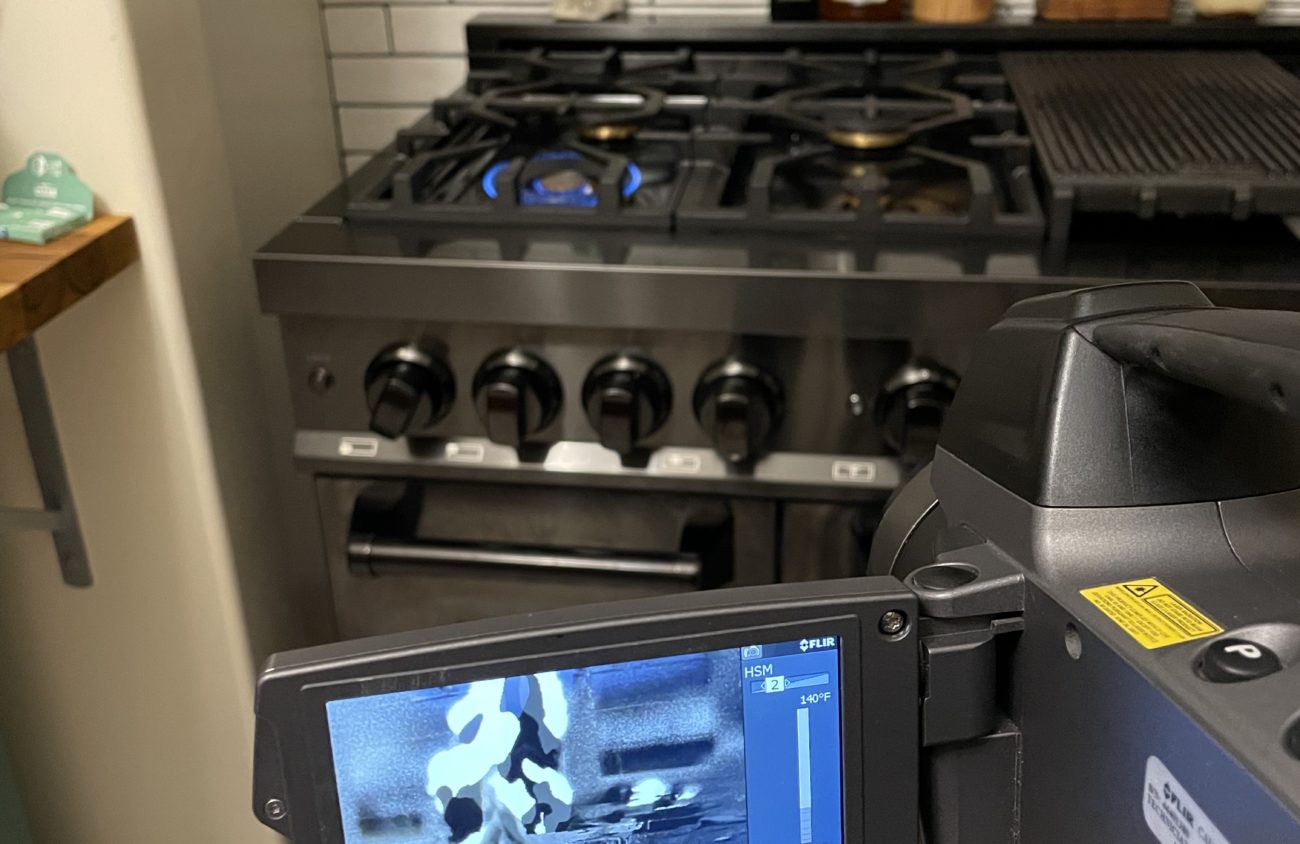 Camera in foreground, gas stove emitting fumes in background